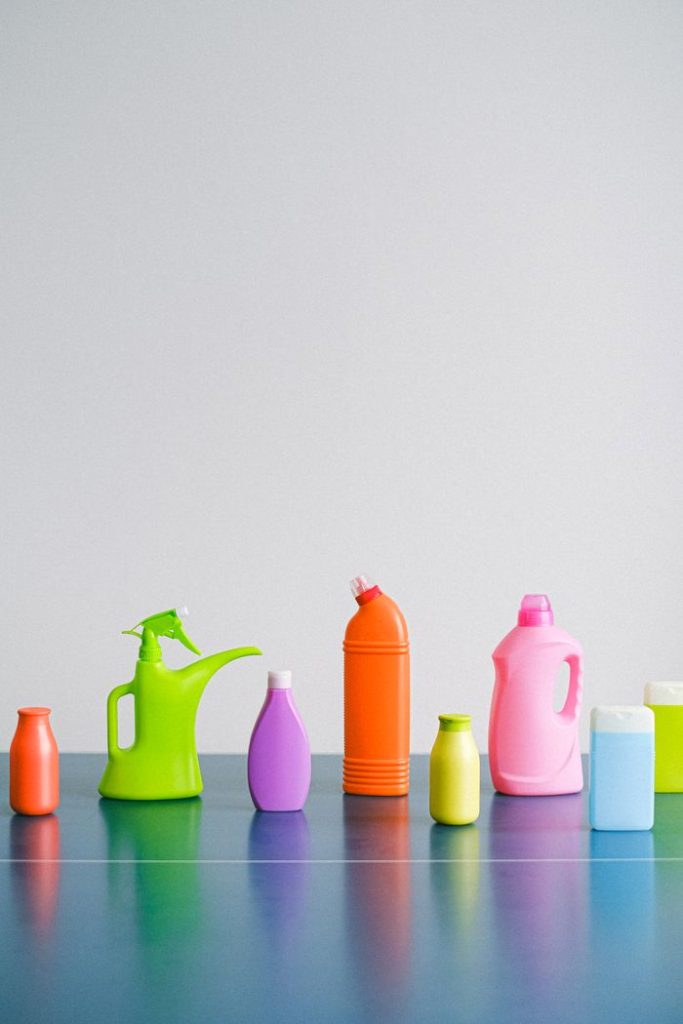 Plastic containers for liquid detergents placed in row on table against gray background